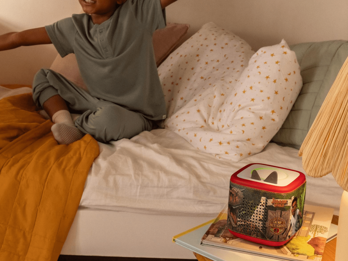 Child playing near a Jurassic Park Sleeve on a red Toniebox 2