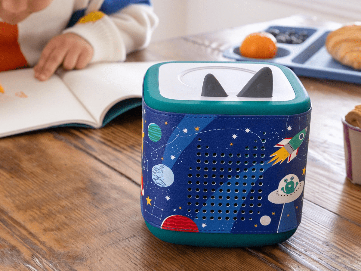 Child reading near Space Sleeve on a teal Toniebox 2