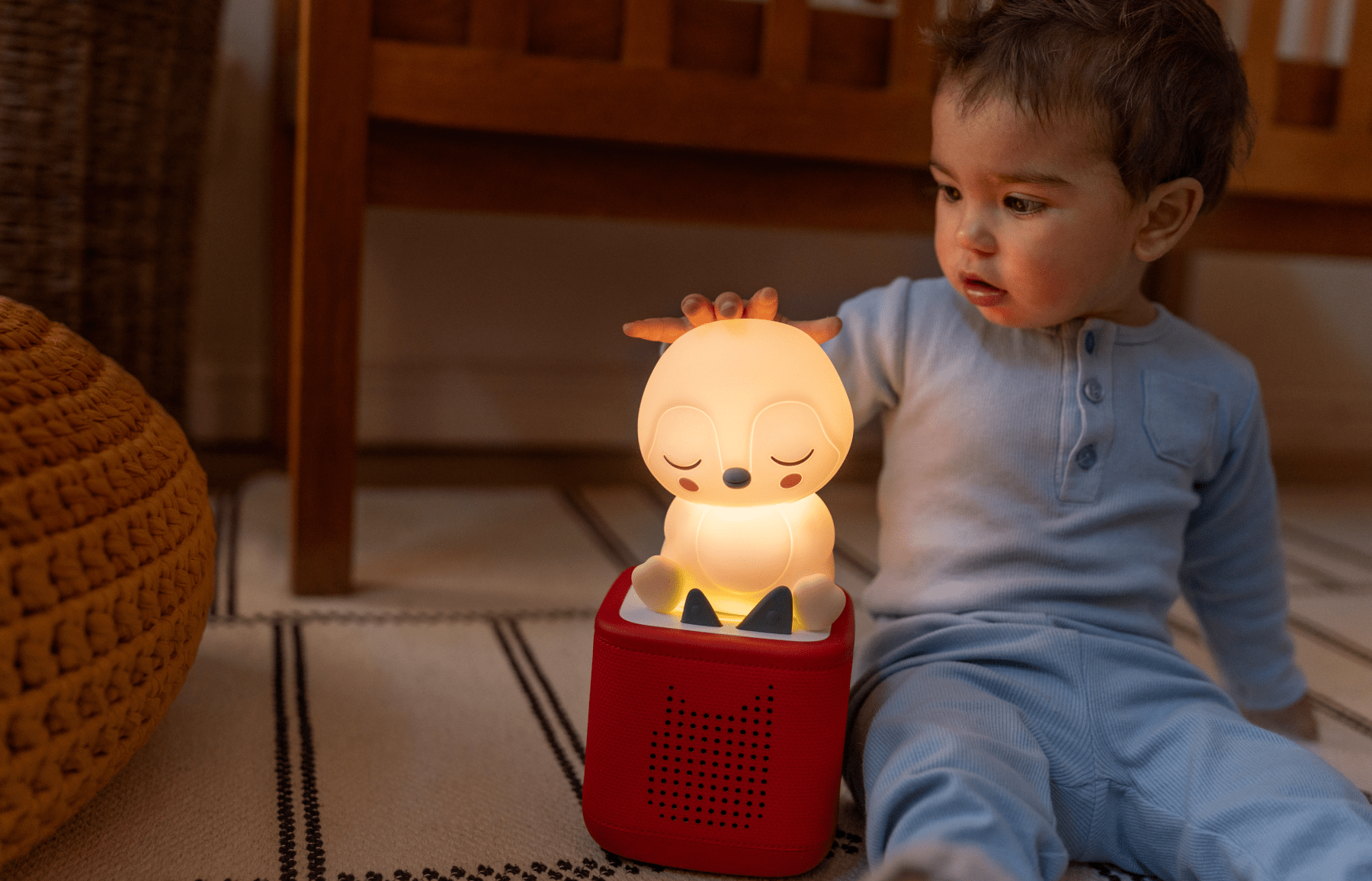 Young child listening to the sleepy penguin night light on a red Toniebox 2