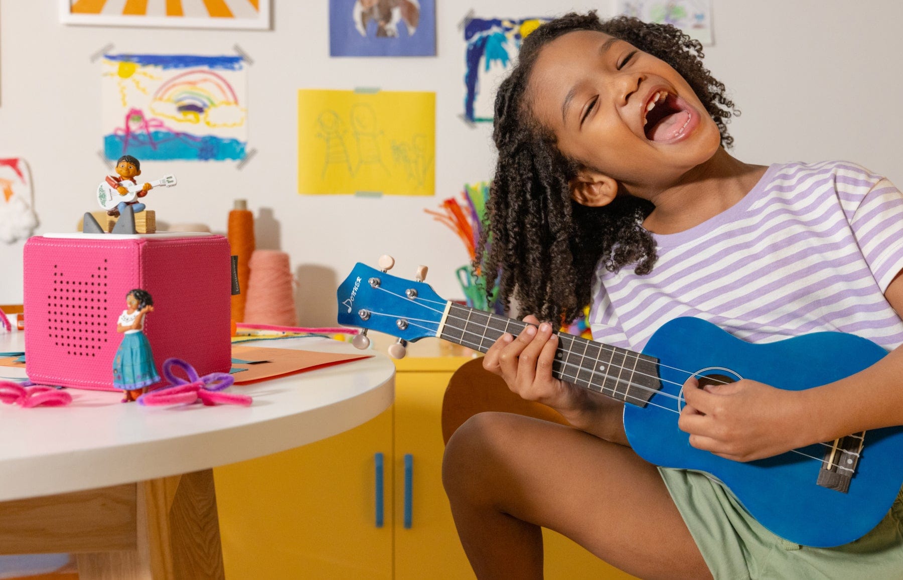 child playing with a guitar and tonies with a pink toniebox