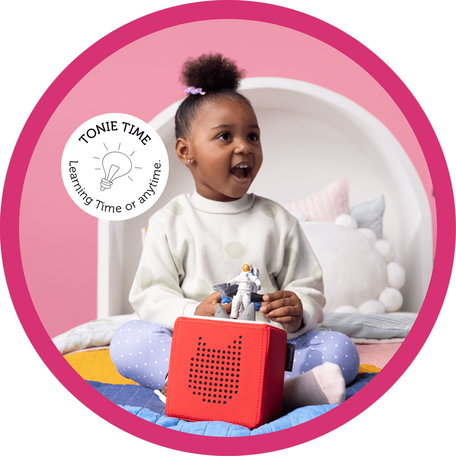 young girl with a red Toniebox on her bed