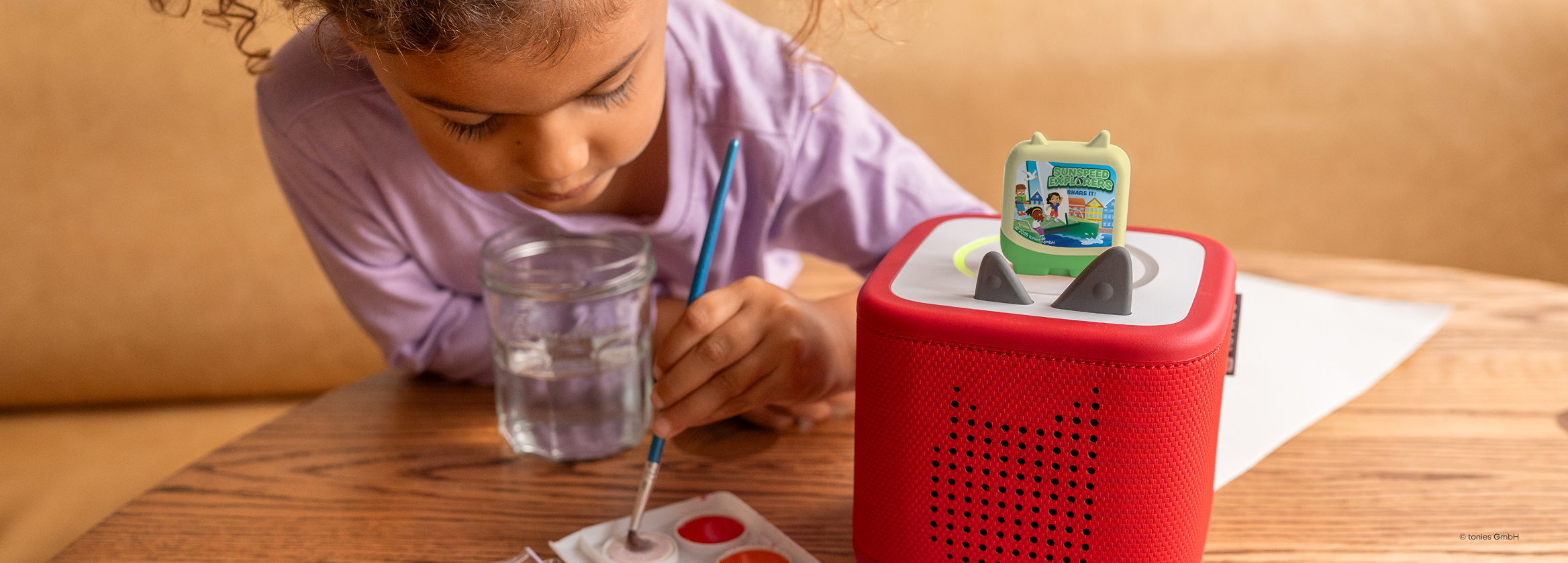 child painting while listening to Sunspeed Explorer Pocket Tonie on a red Toniebox 2