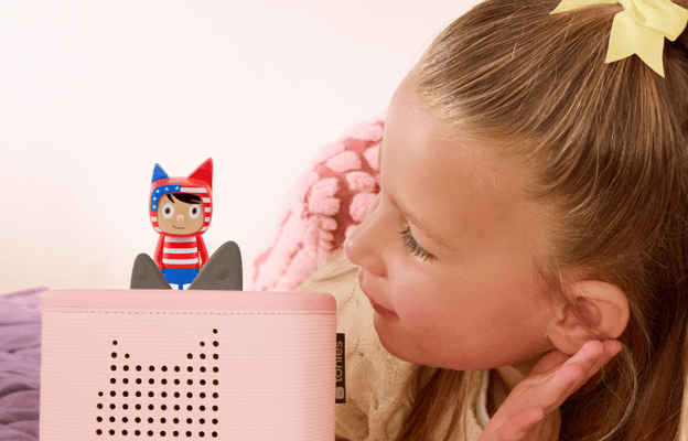 child lying on a bed listening to a 250 anniversary creative tonie on a pink toniebox 2