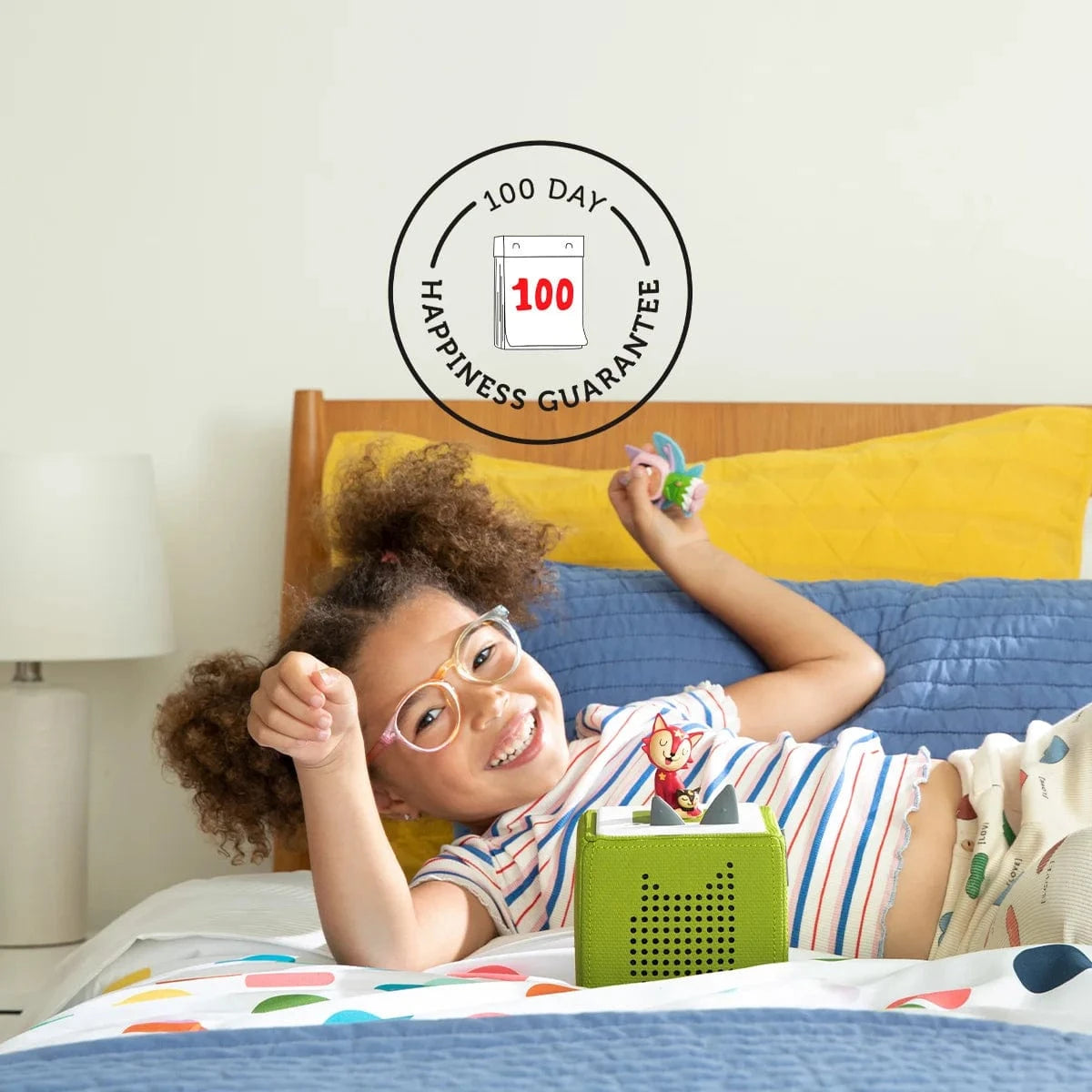 Girl on a bed with her Toniebox enjoying screen free time