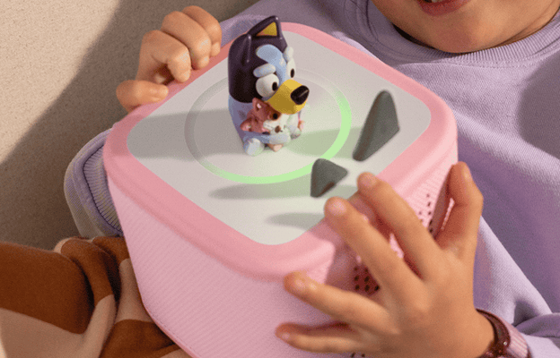 child holding a pink Toniebox 2 with a Bluey Tonie on top