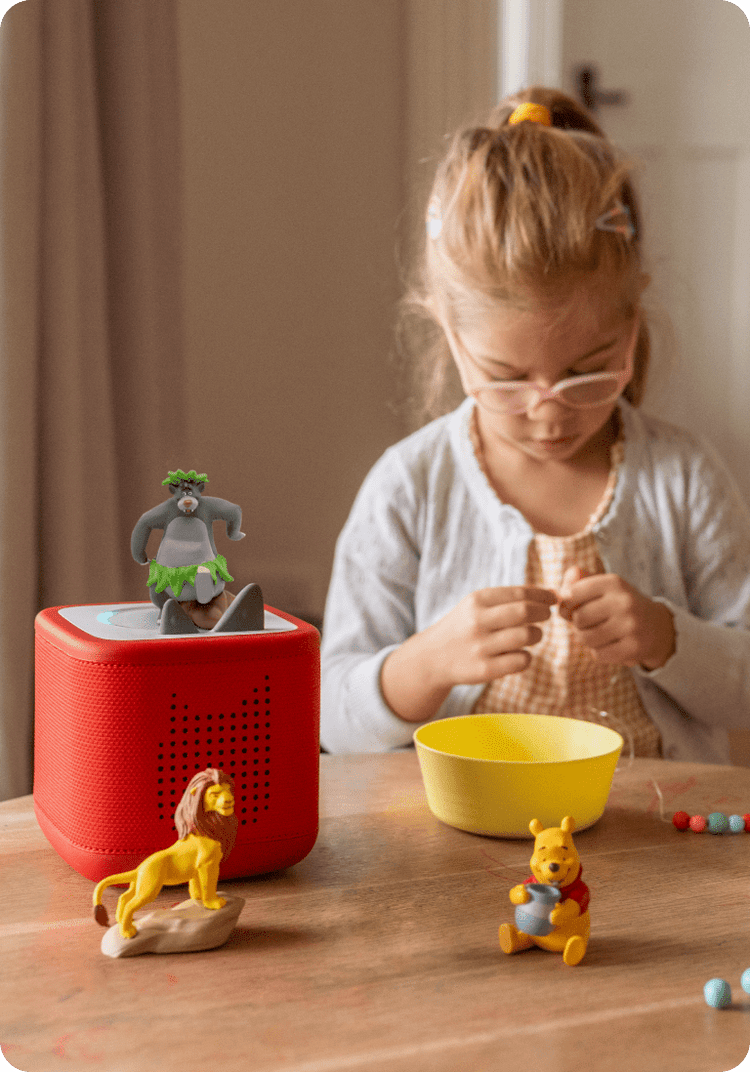 child enjoying craft time while listening to Disney Tonies on their red Toniebox 2