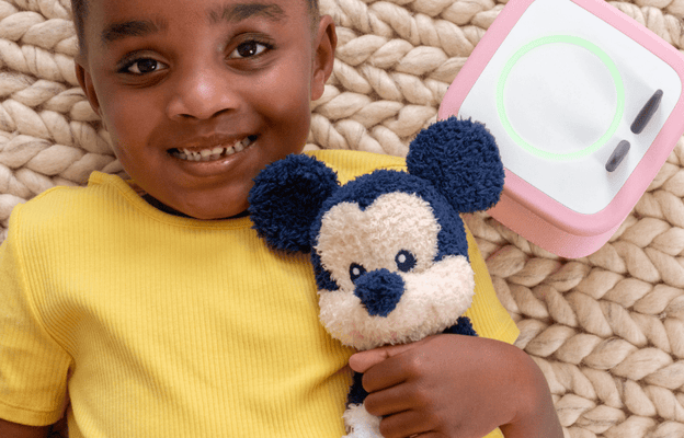 child holding Mickey Cuddle Tonie while laying next to a pink Toniebox 2