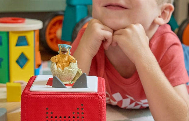 Child playing with a red Toniebox in a playroom