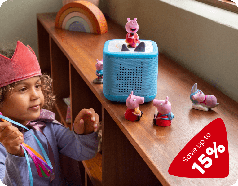 little girl listening to a blue Toniebox 2 and collection of Peppa Pig Tonies