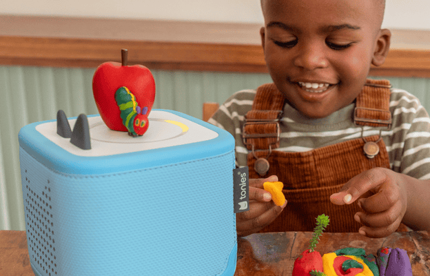 Child listening to a blue Toniebox 2 and The Very Hungry Caterpillar & Friends Tonie while playing with clay