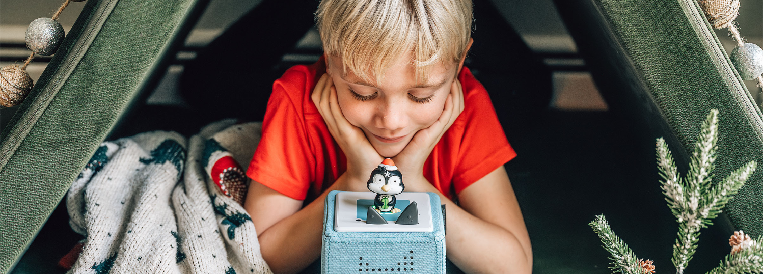 child playing with holiday songs penguin tonie and a blue toniebox