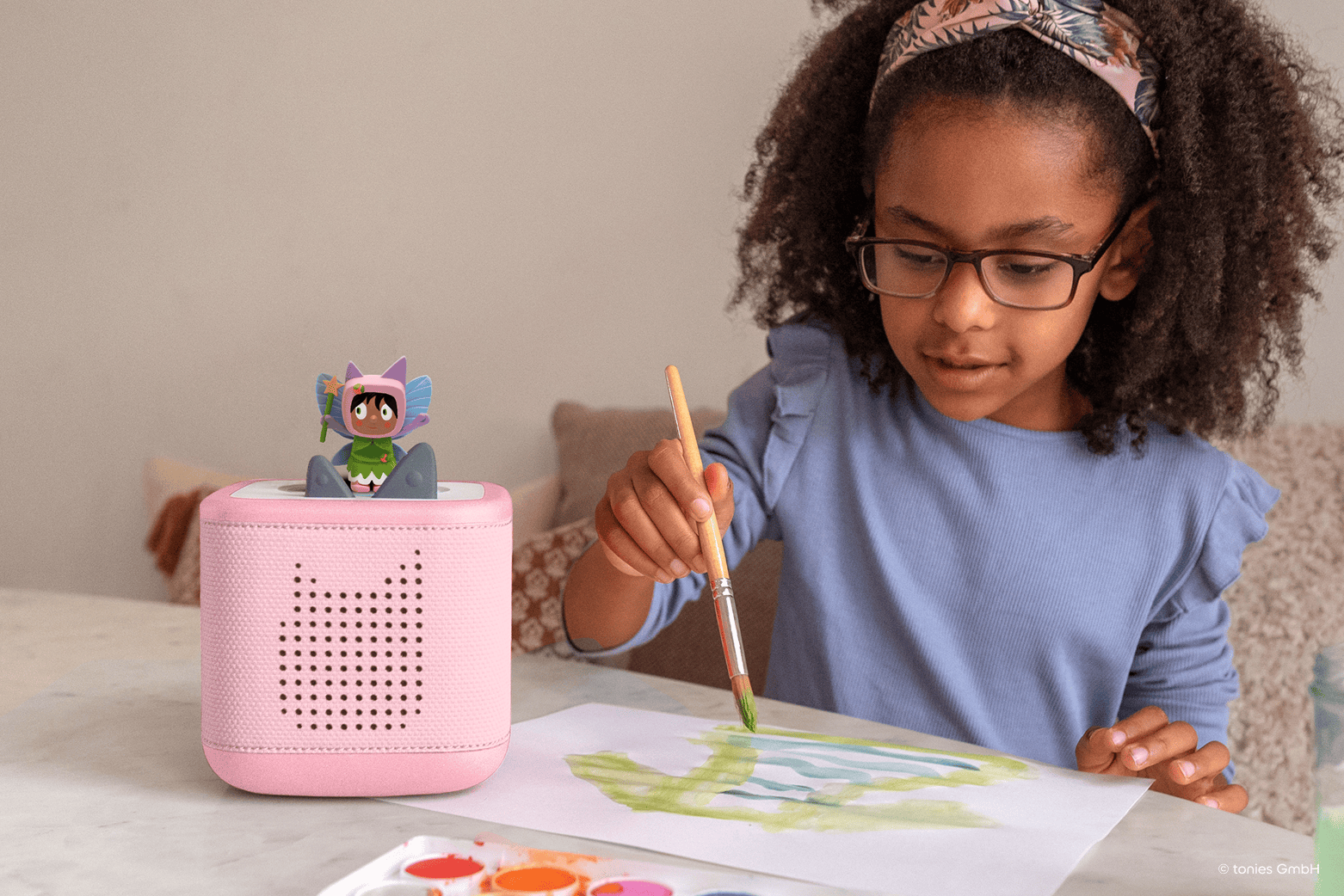 girl listening to a fairy creative tonie on a pink toniebox 2 while painting