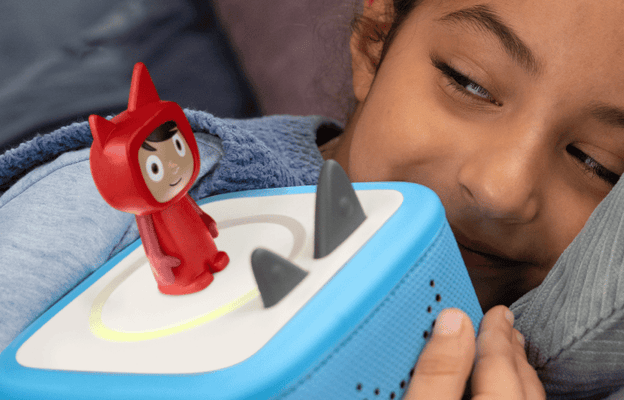 girl holding a blue Toniebox 2 with Creative Tonie on top