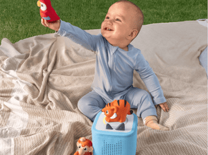 child playing on the ground outside with a toniebox 2 and a my first tonies jungle set