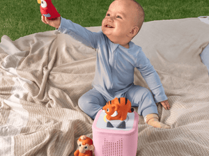 child playing on the ground outside with a toniebox 2 and a my first tonies jungle set