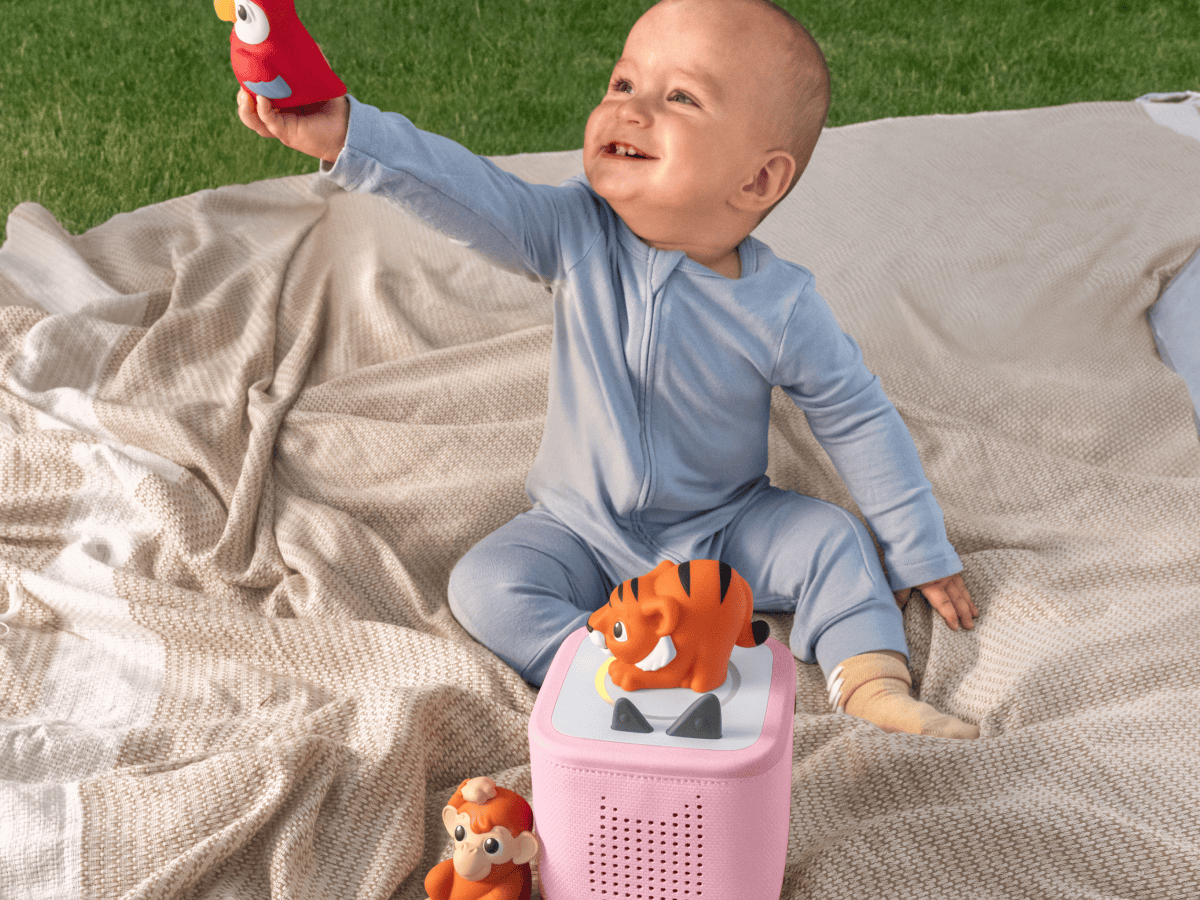 child playing on the ground outside with a toniebox 2 and a my first tonies jungle set