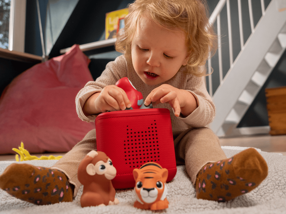 child playing on the floor with a toniebox 2 and a my first tonies jungle set