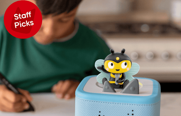 Child sitting at a table with a blue Toniebox 2 featuring the Bugs Tonie, in a kitchen setting.