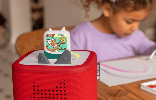 child drawing while listening to Letter Carriers Pocket Tonie on a red Toniebox 2