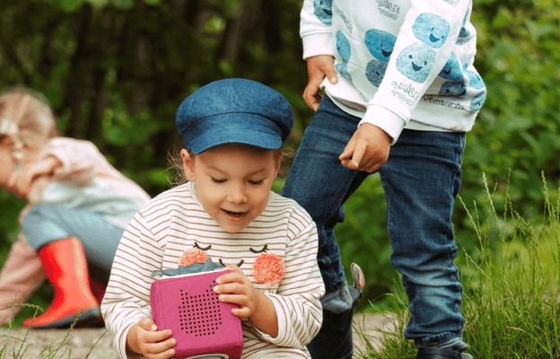 Kids playing outside while listening to a Toniebox