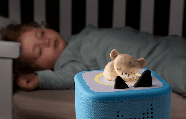 child sleeping in bed with a blue Toniebox 2 playing sleepy friend tonie nearby