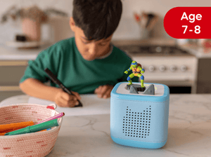 Child playing with a blue Tonies on a kitchen counter, with a red age label indicating 7-8 years.