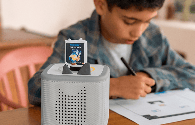 child sitting at a table drawing while listening to the Minecraft audiobooks for kids on a grey Toniebox 2