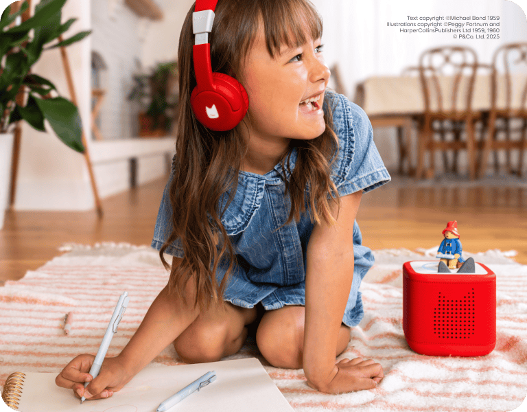 child wearing red tonies bluetooth headphones listening to Paddington Tonie on a red Toniebox 2