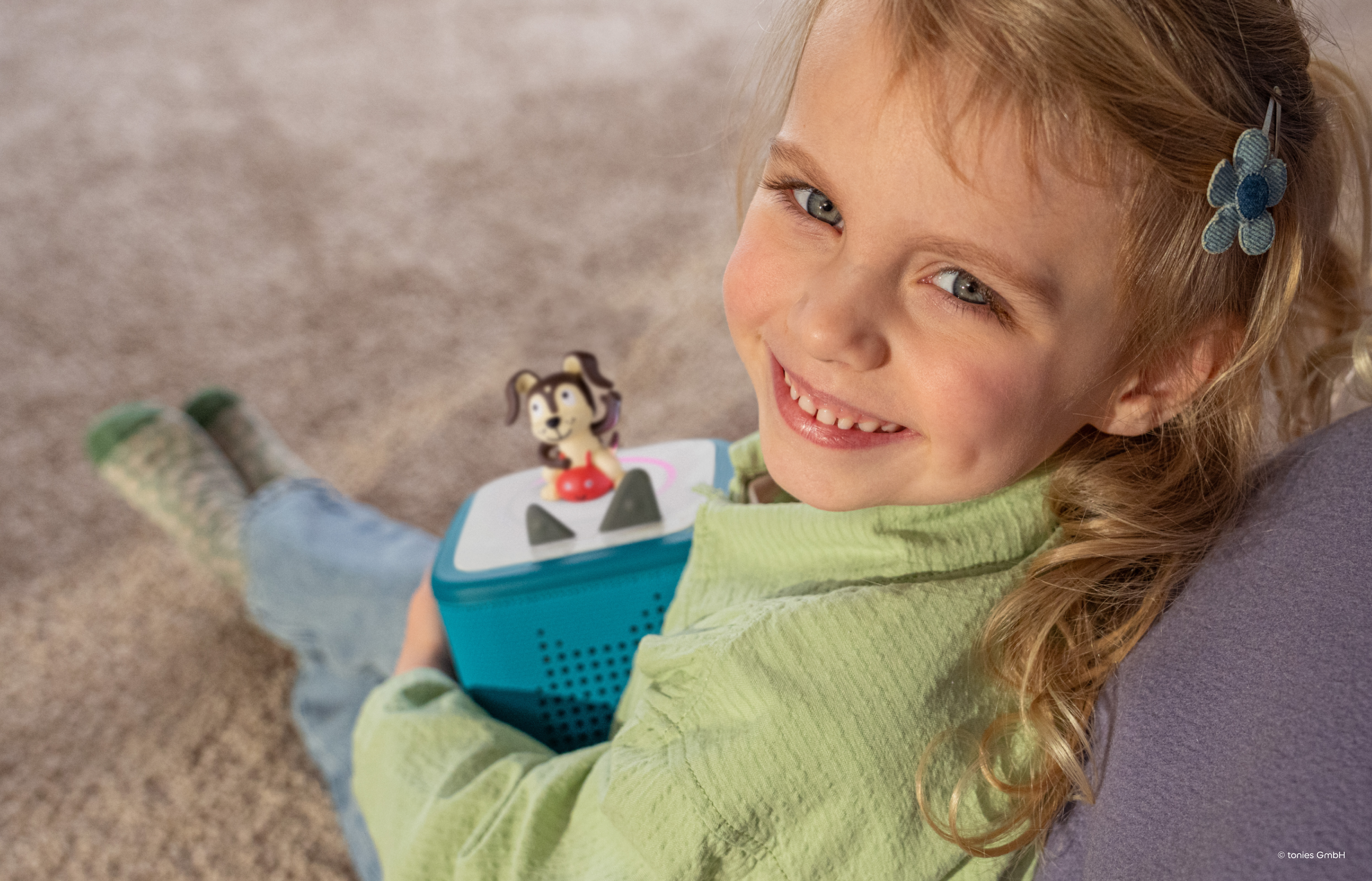 Girl holding a teal Toniebox 2 while the playtime puppy tonie is playing
