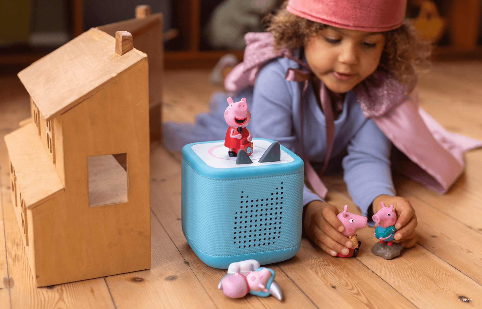 child playing with Peppa Pig Tonies while listening to a blue Toniebox 2