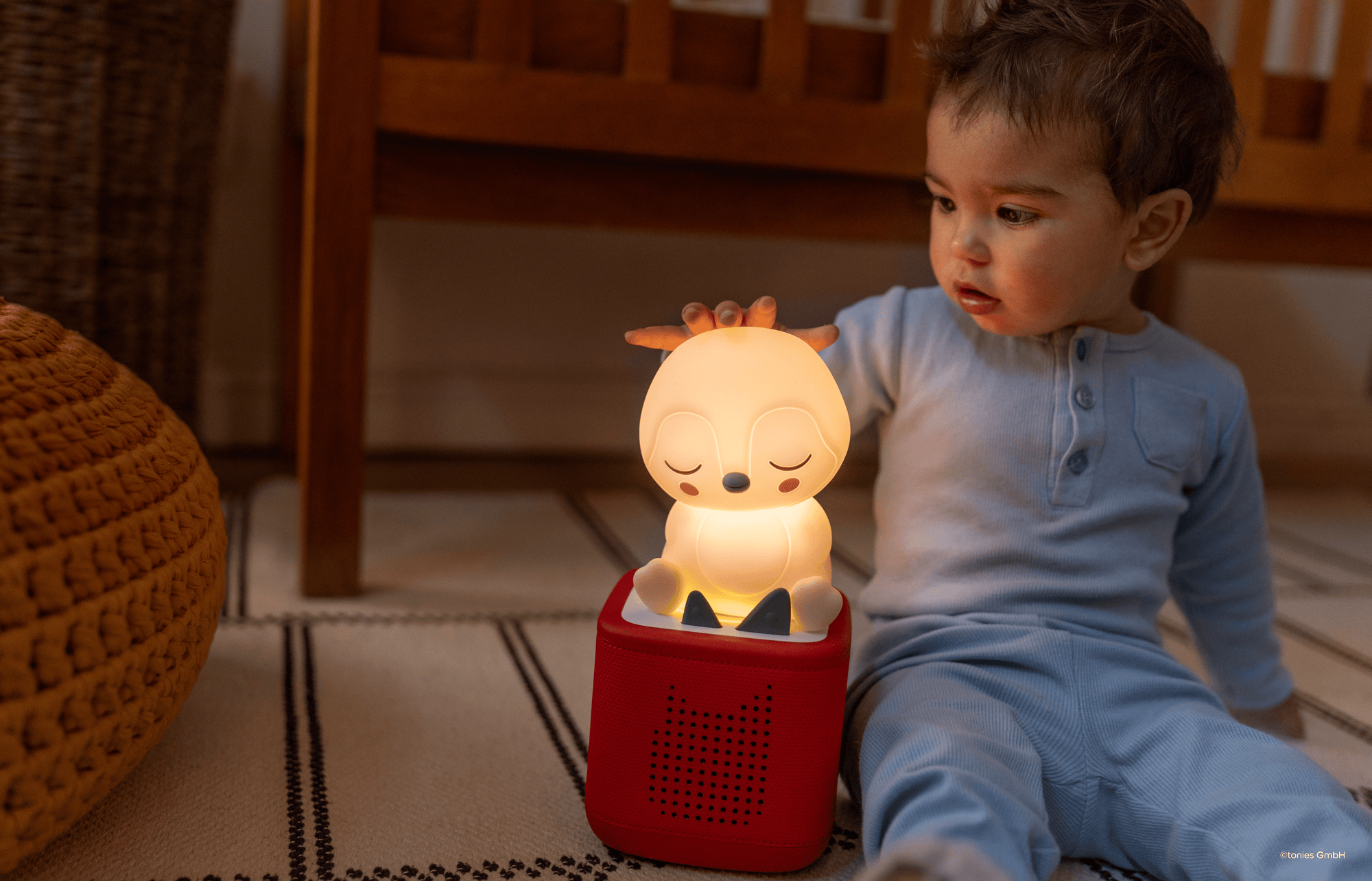Young child listening to the sleepy penguin night light on a red Toniebox 2
