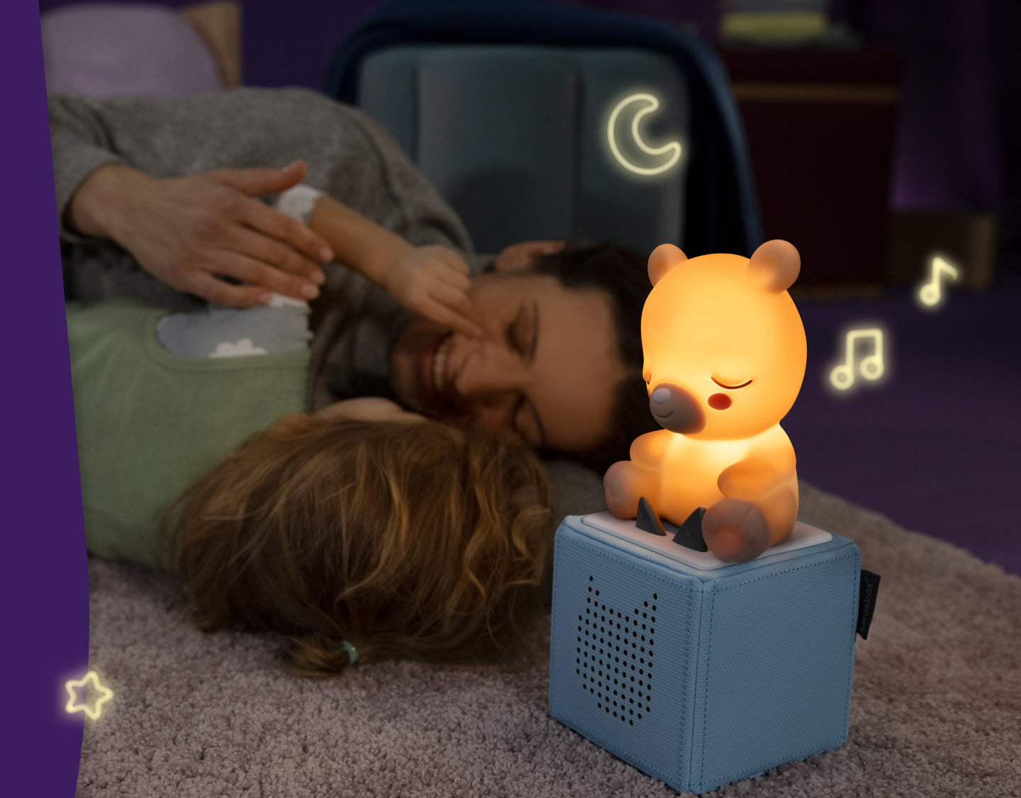 child and parent playing next to a sleepy bear night light tonie on a blue toniebox