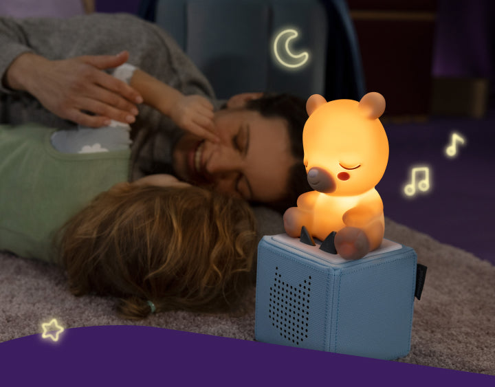 child and parent playing next to a sleepy bear night light tonie on a blue toniebox