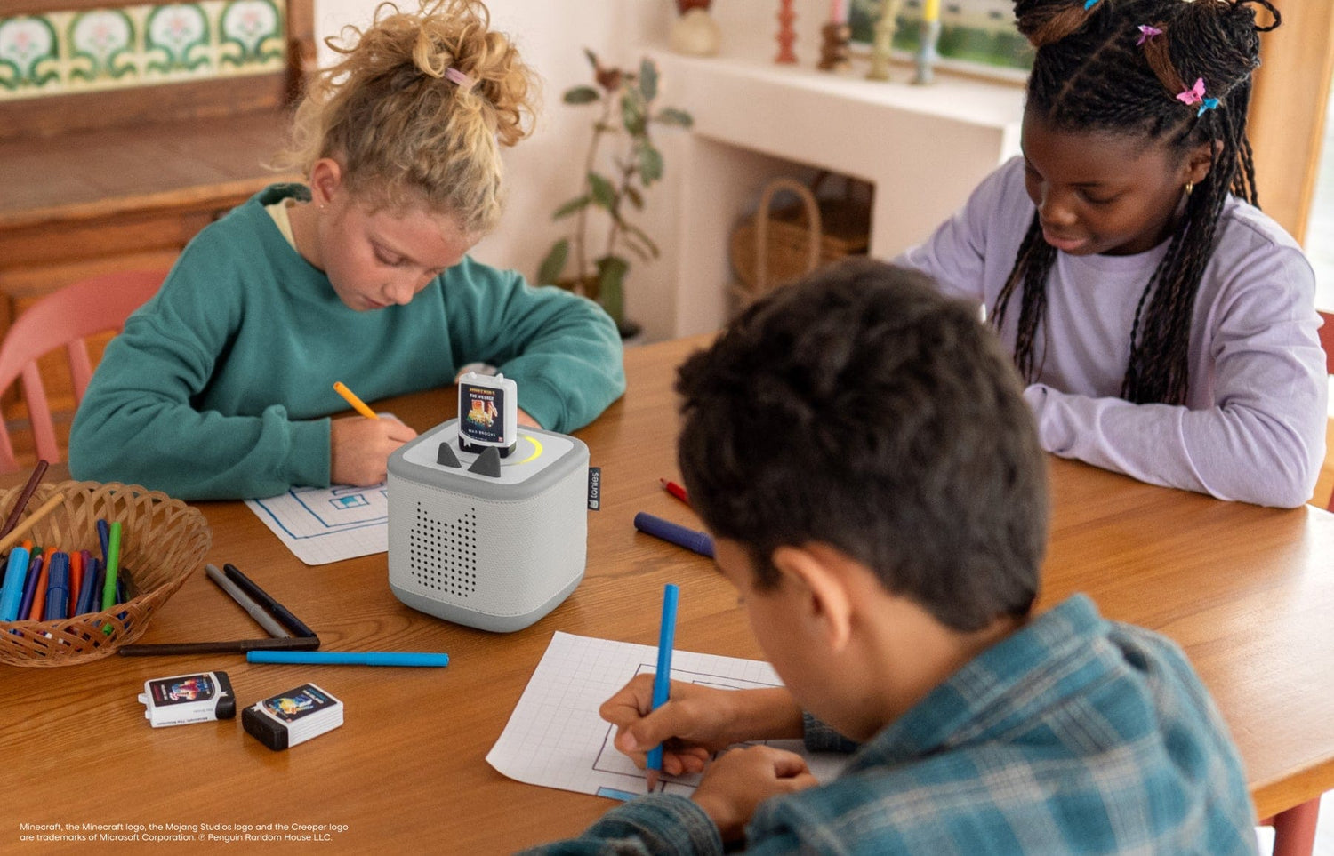 three children coloring while listening to Minecraft audiobooks for kids on a grey Toniebox 2