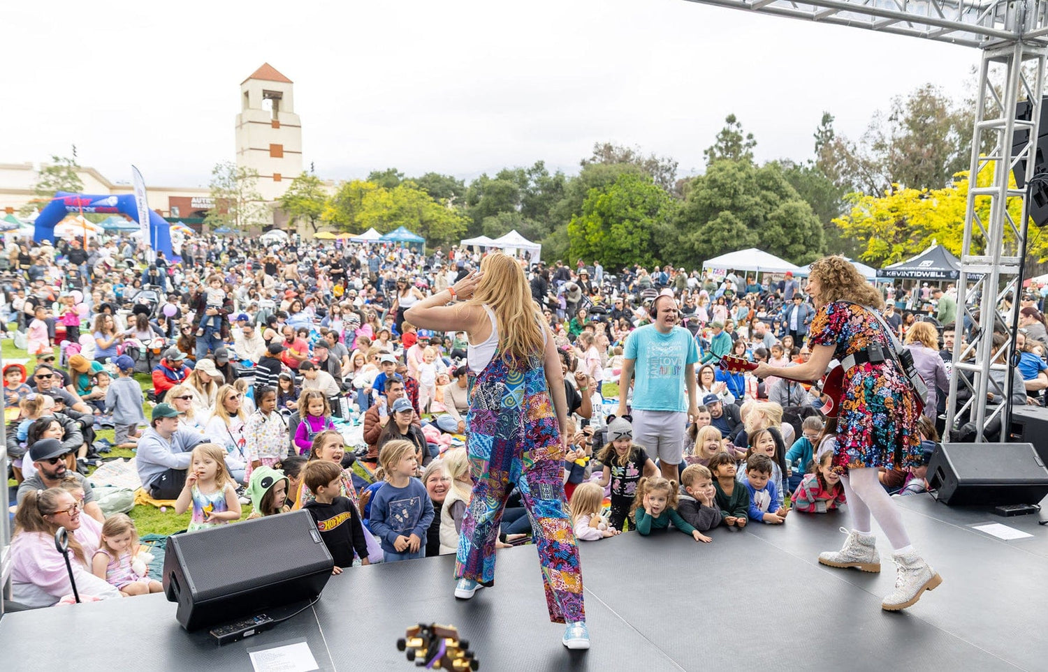 Laurie Berkner performing in a park in front of a crowd of children and parents