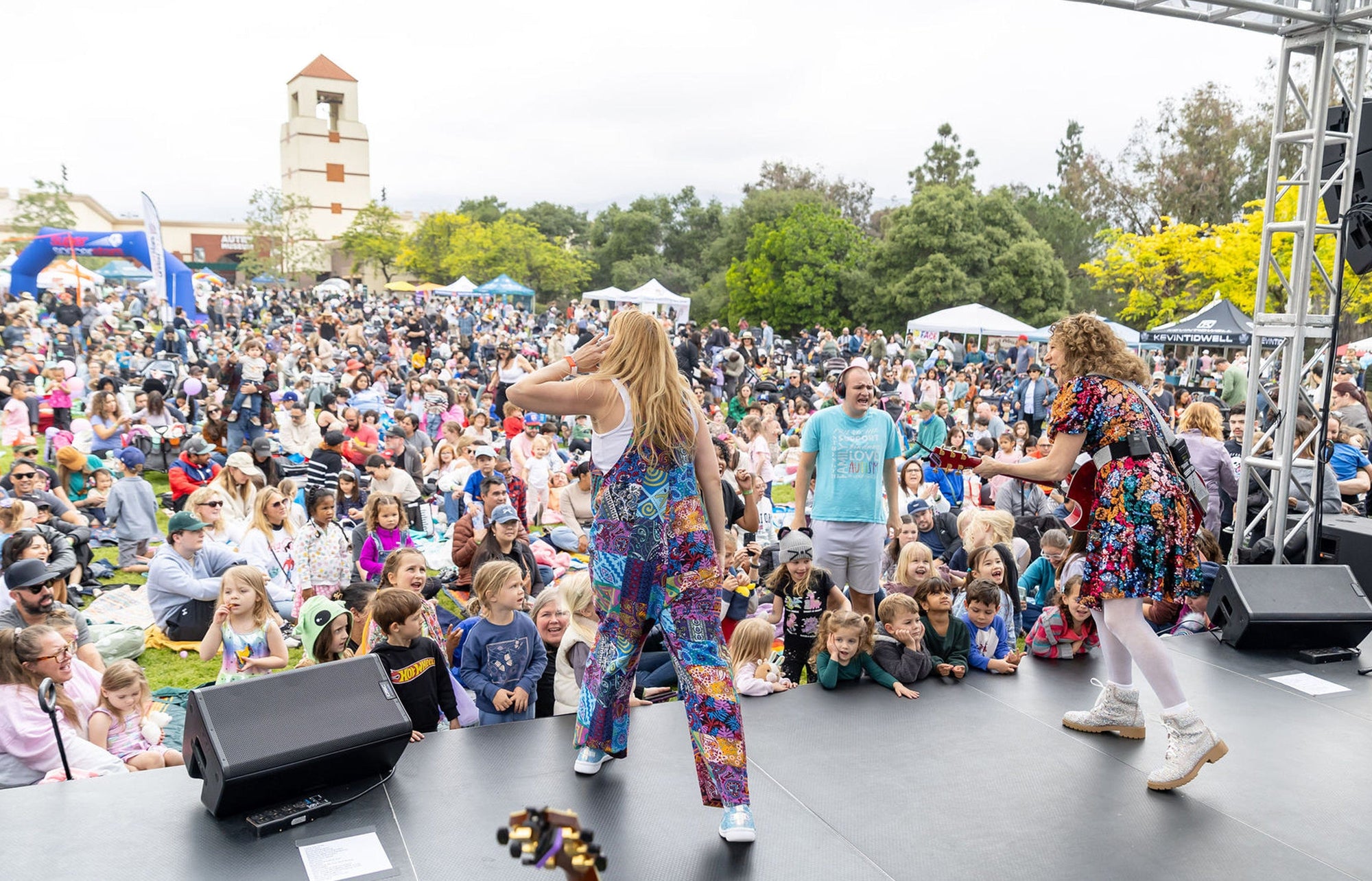 Laurie Berkner performing in a park in front of a crowd of children and parents