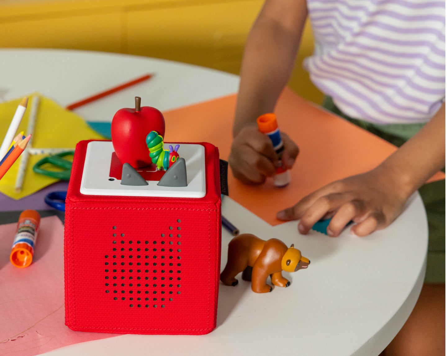 child playing and coloring with tonies and a red toniebox