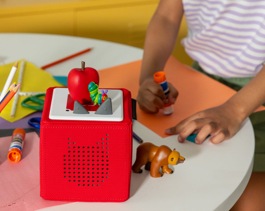 child playing and coloring with tonies and a red toniebox