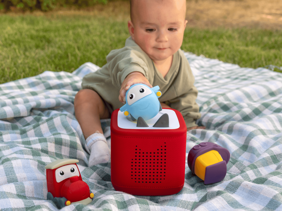 child playing on the ground outside with a toniebox 2 and a my first tonies travel set