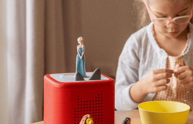 little girl listening to a red Toniebox 2 and a range of Disney Tonies while enjoying craft time
