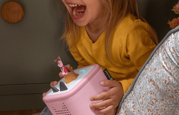 child playing in a pillow fort with a pink Toniebox 2 listening to the Piglet Tonie