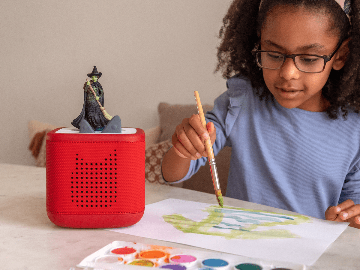 Child playing with Wicked Tonie audio figurine and Toniebox 2