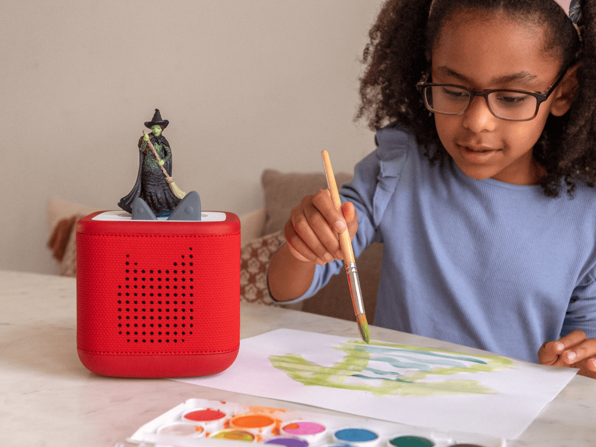 Child playing with Wicked Tonie audio figurine and Toniebox 2