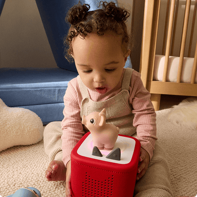 little girl listening to the Pig My First Tonie on a red Toniebox 2