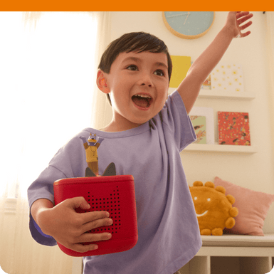 child holding a red Toniebox 2 while listening to the Doggyland Tonie