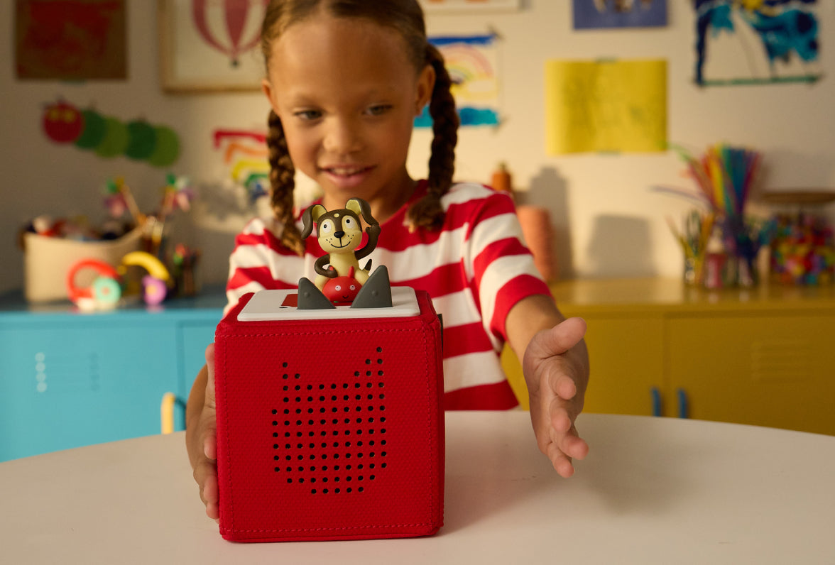 child smiling putting the playtime puppy tonie on a red toniebox