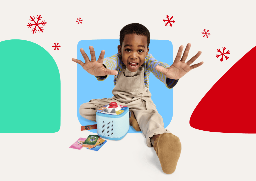 Child with blue Toniebox 2 and Tonieplay game with holiday snowflakes and shapes in the background